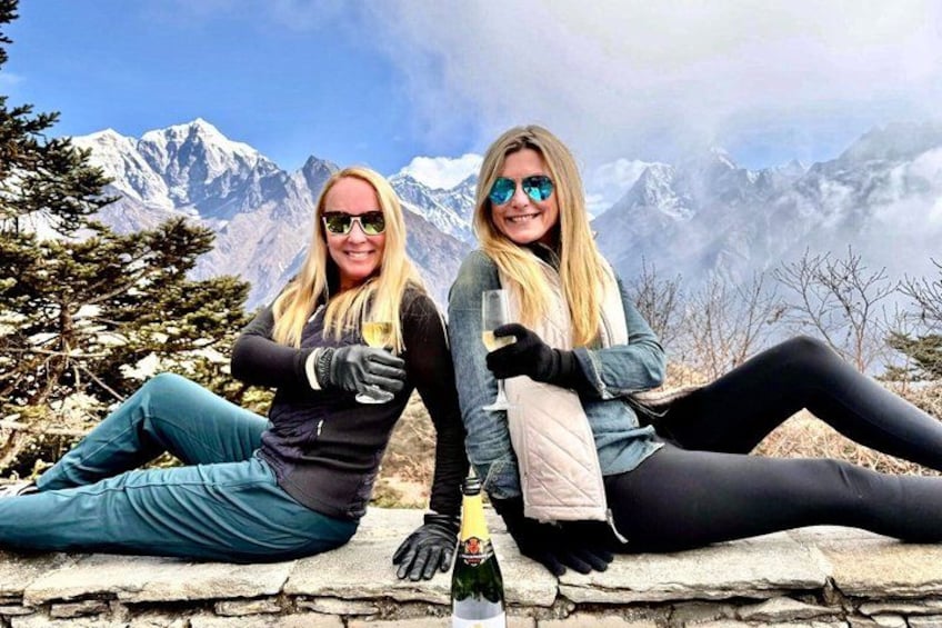 Two people sitting on a stone ledge with a mountainous landscape in the background. 5
