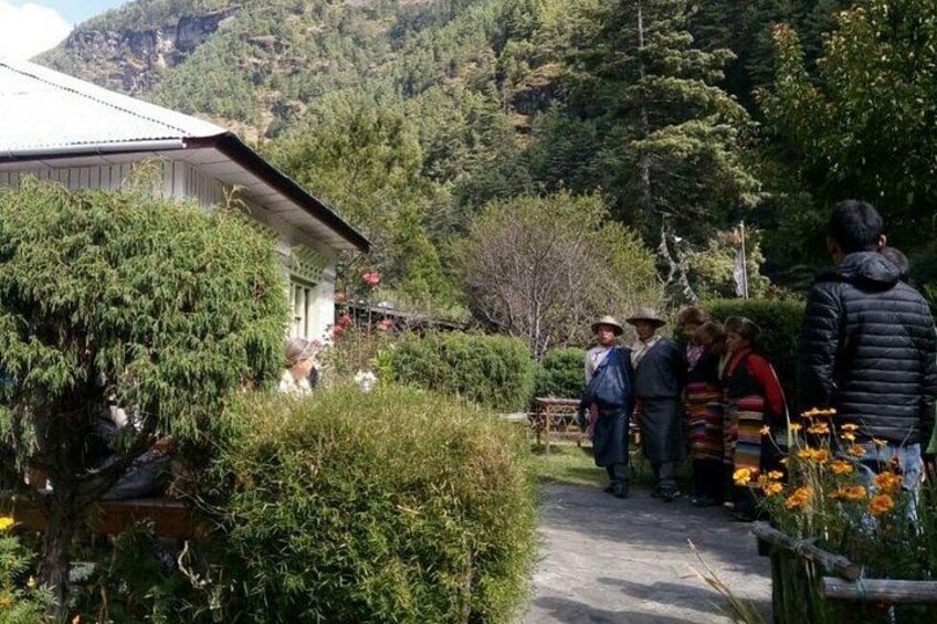 Un gruppo di persone in piedi all'aperto vicino a un edificio circondato da vegetazione e colline. 2