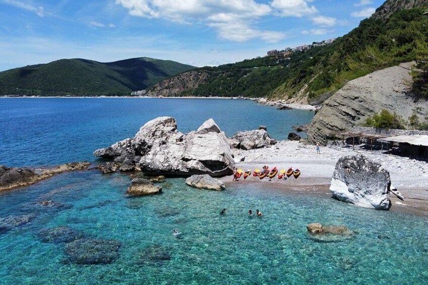 Budva Bay Kayak & SUP Tour to Coastal Caves – kayaks and guests resting on a pebble shore at Calipso Beach, Montenegro 3