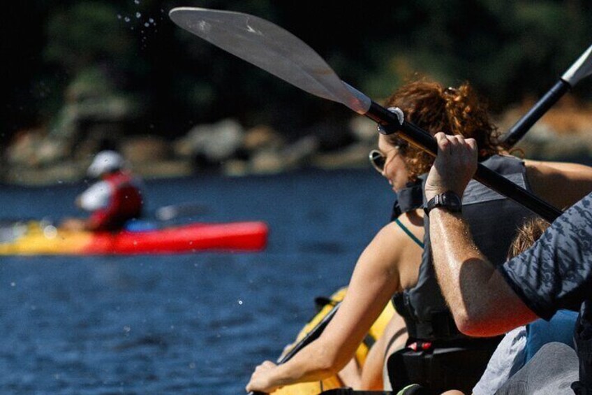 A person kayaking on a river with another person in a kayak in the background. 4