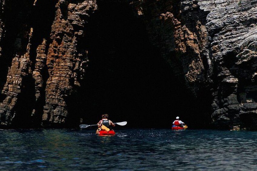 Budva Bay Kayak & SUP Tour to Coastal Caves – two paddlers in orange kayaks entering a sea cave in Budva Bay, Montenegro 3