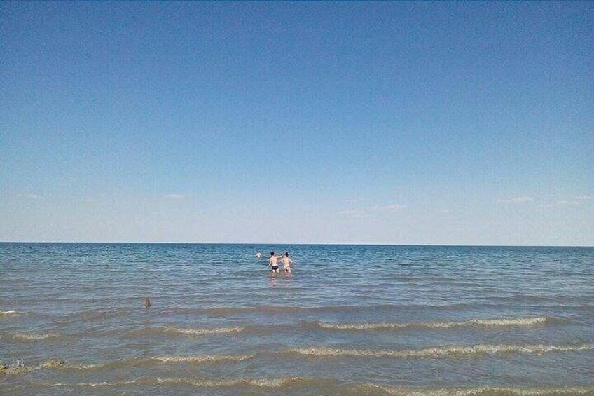 A calm sea with two people wading in shallow water. 2