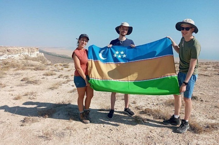 Three people holding a flag in a desert landscape. 5