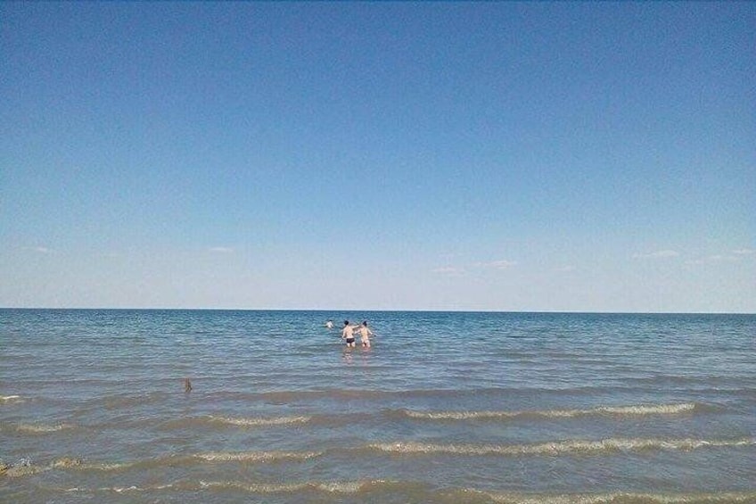 A calm sea with two people in the distance. 2