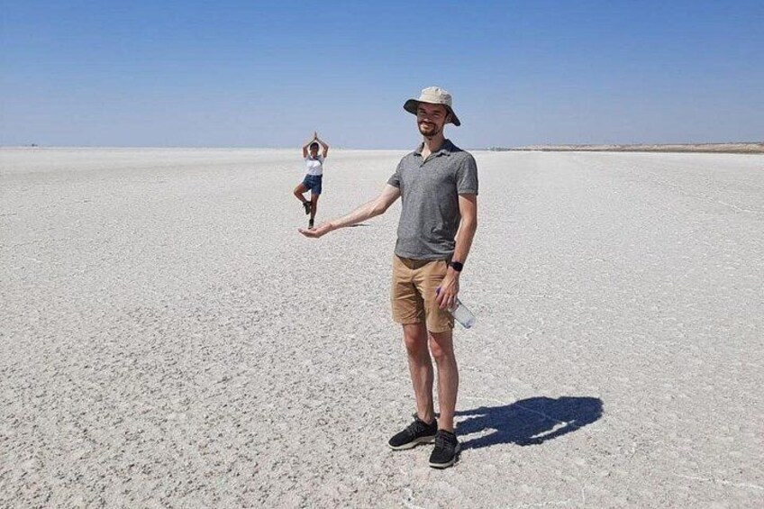 A person standing on a salt flat with a child in the background. 4