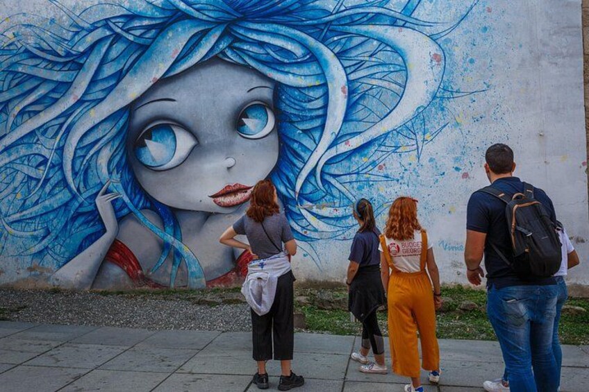 Un mural que muestra a una chica de cabello azul y vestido rojo en una pared. 4