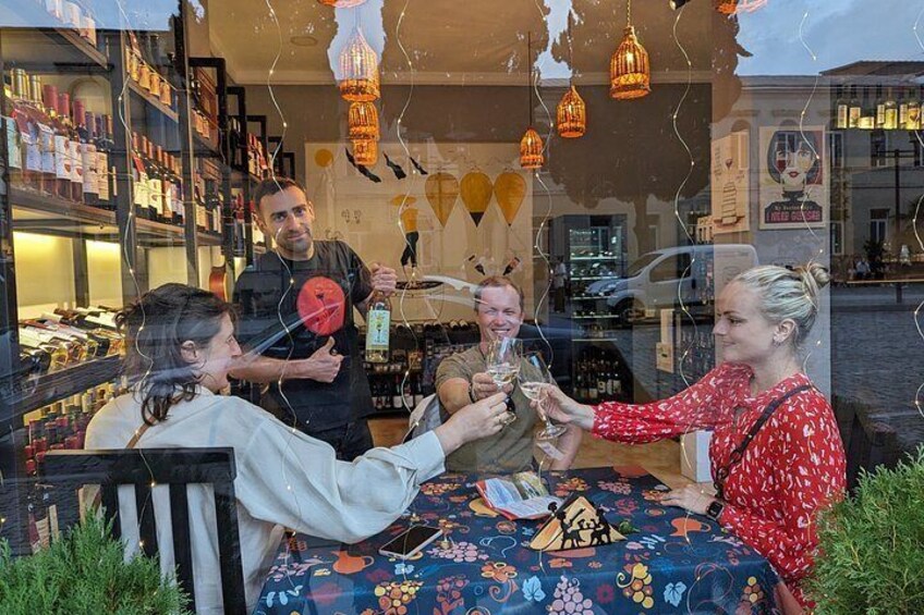 Un grupo de personas brindando en una mesa con mantel estampado, rodeado de estantes con productos. 5