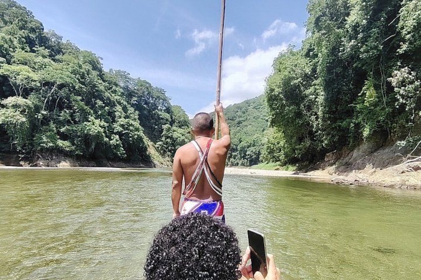 A person in a river, holding onto a rope, with a forested hillside in the background. 2