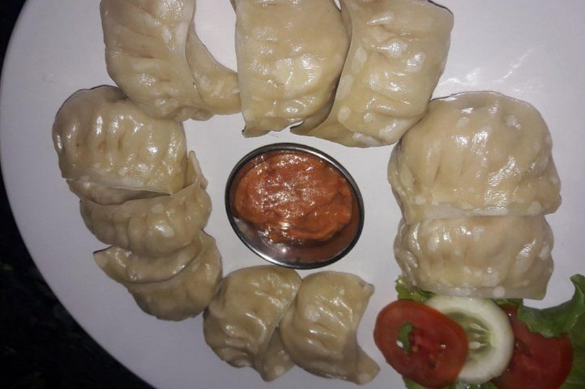 Un plato de dumplings con salsa para mojar y una ensalada acompañante. 1
