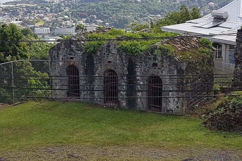 A stone building with arched windows, surrounded by a fence and greenery. 3