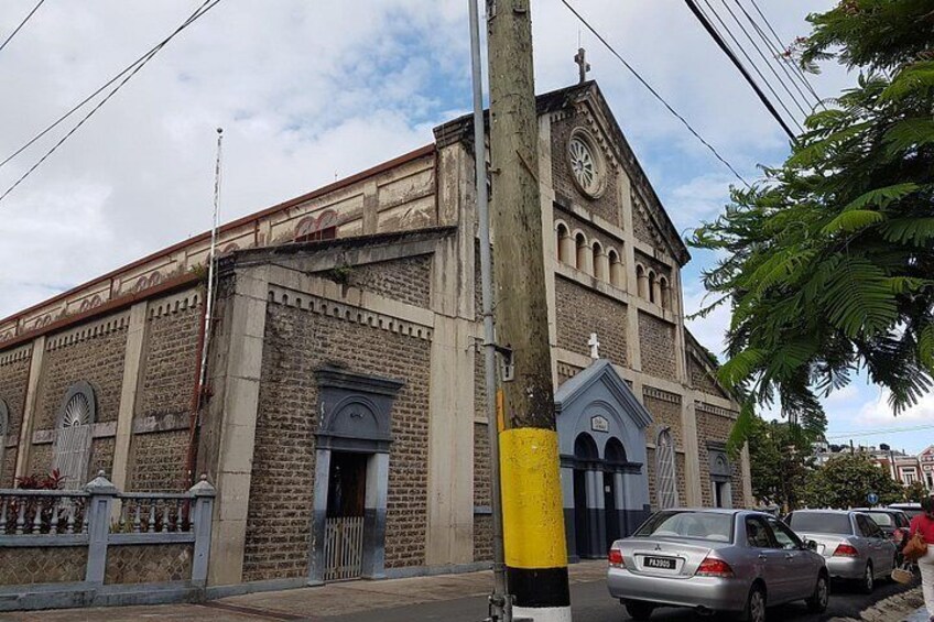 A church with a clock tower, a yellow pole, and parked cars. 4
