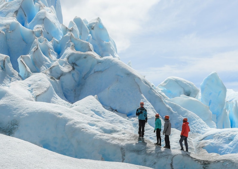 A group of people standing on a snow-covered glacier with ice formations. 3