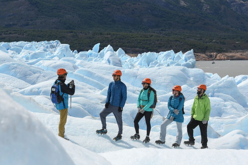 A group of people ice skating on a glacier with mountains in the background. 4