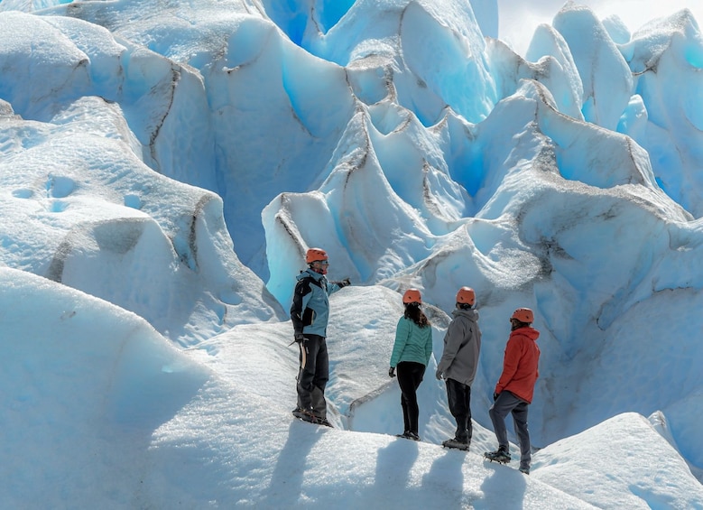 A group of people standing on a snow-covered glacier with ice formations in the background. 2