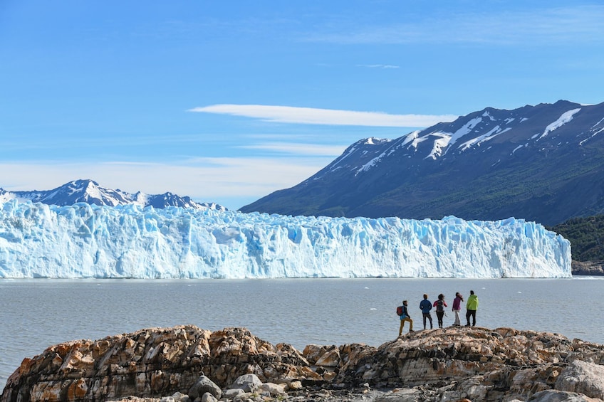 A glacier with people standing on a rocky outcrop in the foreground. 5
