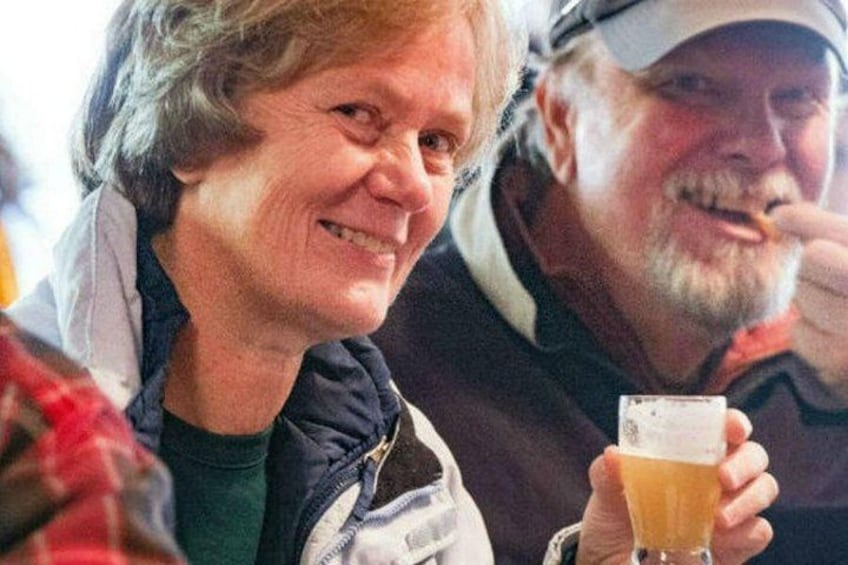 Una persona che tiene un bicchiere di birra, un'altra persona sullo sfondo e una camicia a quadri. 3