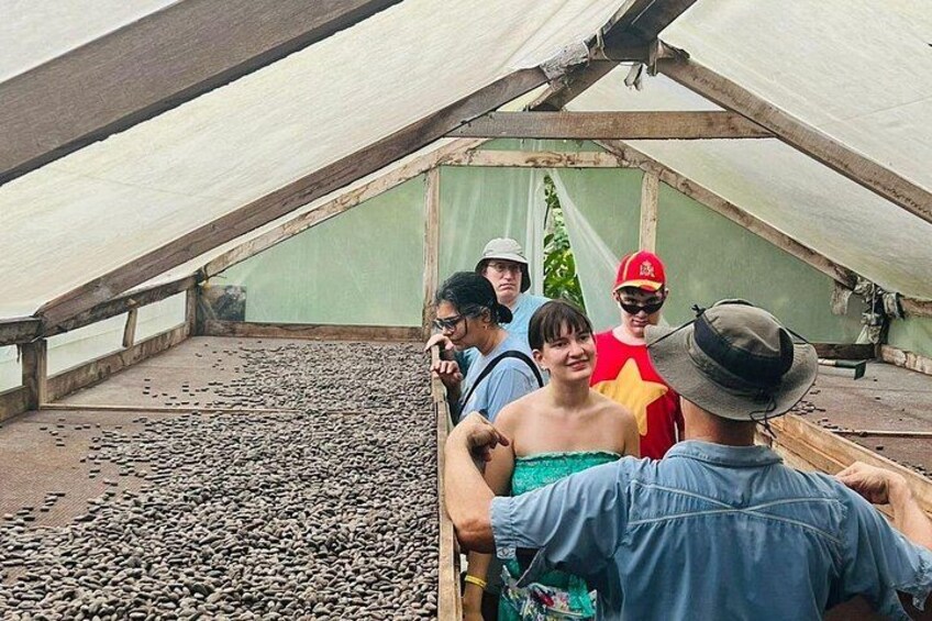 Un grupo de personas dentro de una estructura tipo tienda con techo inclinado, sobre un piso de grava. 4