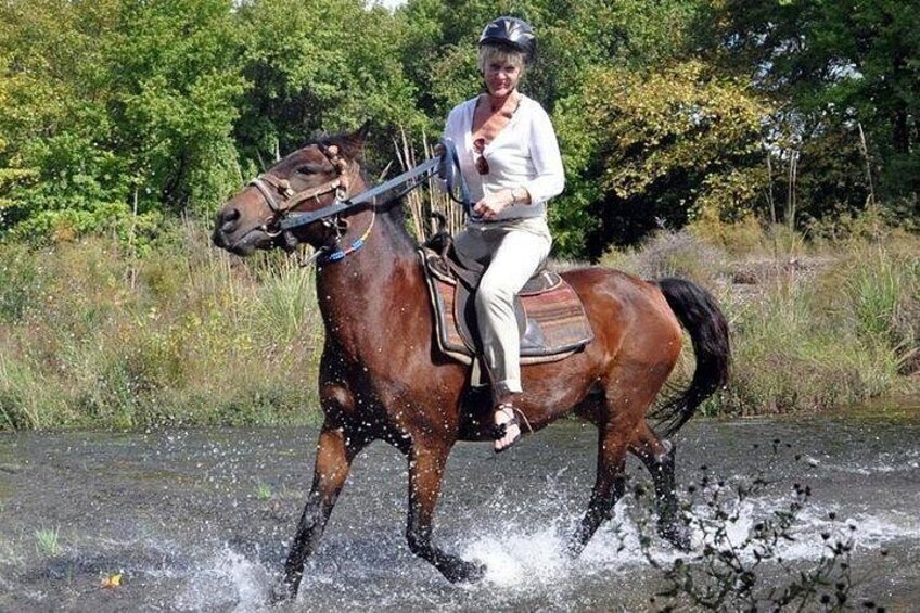 En person rider hest på en vej, hvor vand sprøjter til siderne. 5