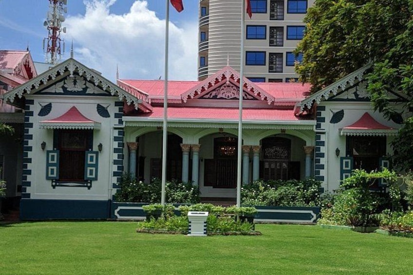 A building with a red roof and green and white walls, surrounded by a well-maintained lawn. 1