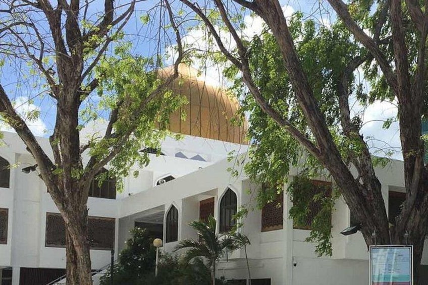 A white building with a dome and arched windows, surrounded by trees. 3