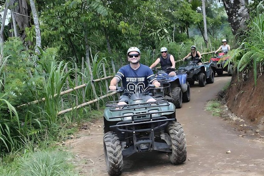 A group of people riding ATVs on a dirt path surrounded by greenery. 2