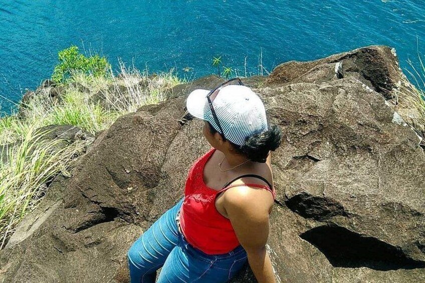 A person sitting on a rock by a body of water. 2