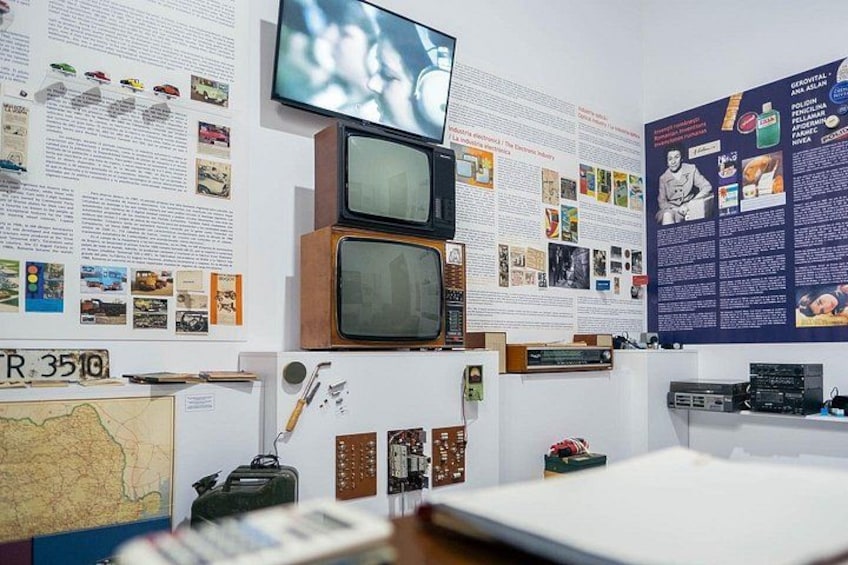 A room with vintage televisions, a map, and informational posters. 4