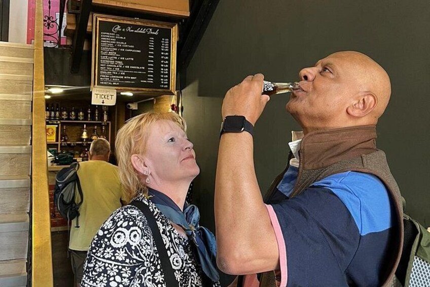 A person holding a microphone, another person looking up at them, and a menu board in the background. 4