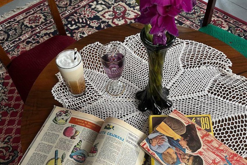 A table with a book, a glass of iced coffee, a glass of water, and a vase with flowers. 2