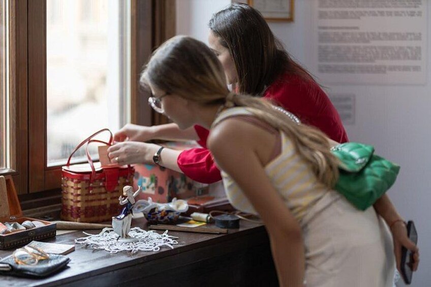 A person at a table with a basket, a figurine, and a green bag. 3