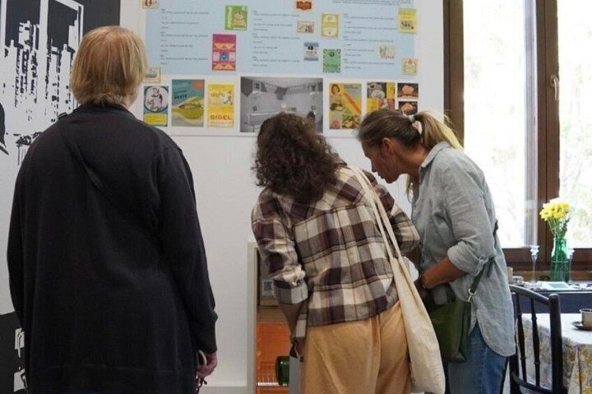 Three people at an indoor event, with posters and papers on the wall. 2
