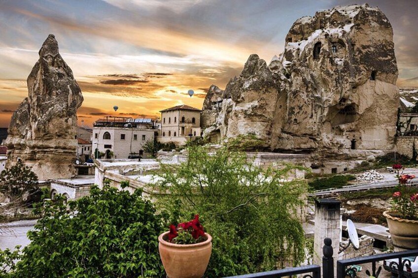 Paesaggio roccioso con un villaggio, una grande formazione rocciosa e un tramonto. 2