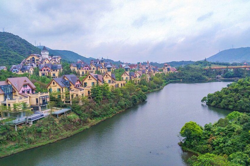 A river with houses along its banks, surrounded by greenery and hills. 3