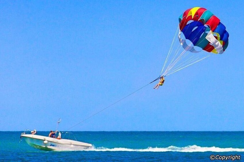 A person parasailing over the ocean, connected to a boat. 2