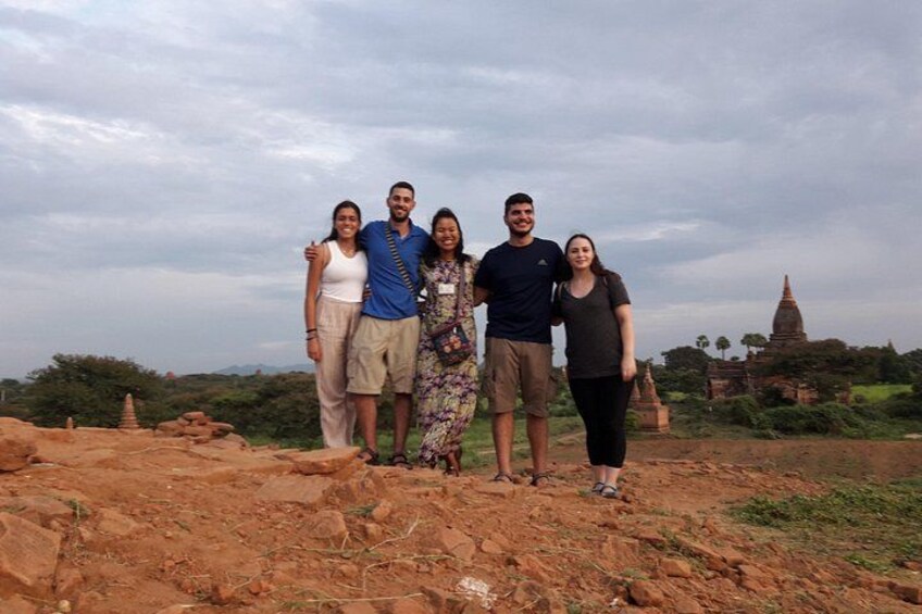 A group of people standing on a rocky terrain with a temple in the background. 3