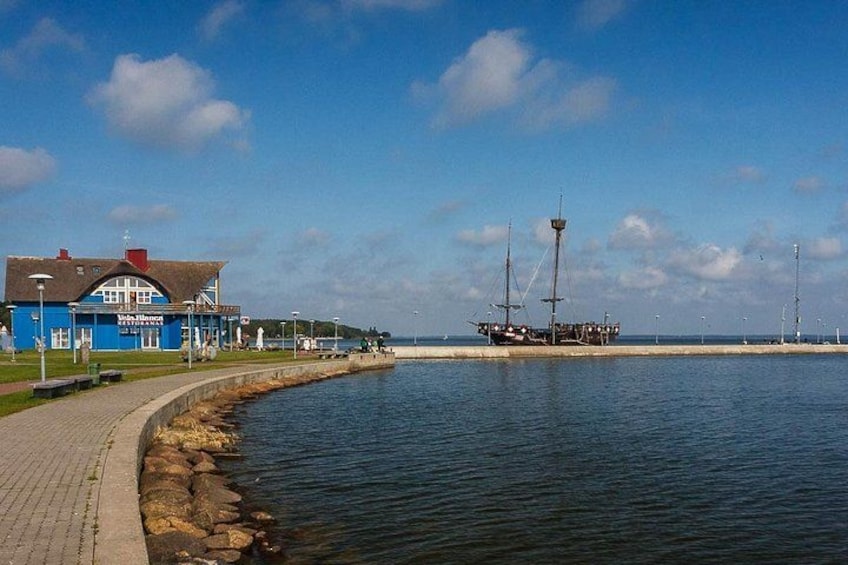A waterfront with a blue building, a pier, and a ship. 1