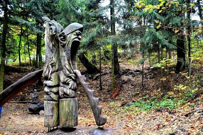 En skov med en træskulptur af en figur, der holder en stav. 2