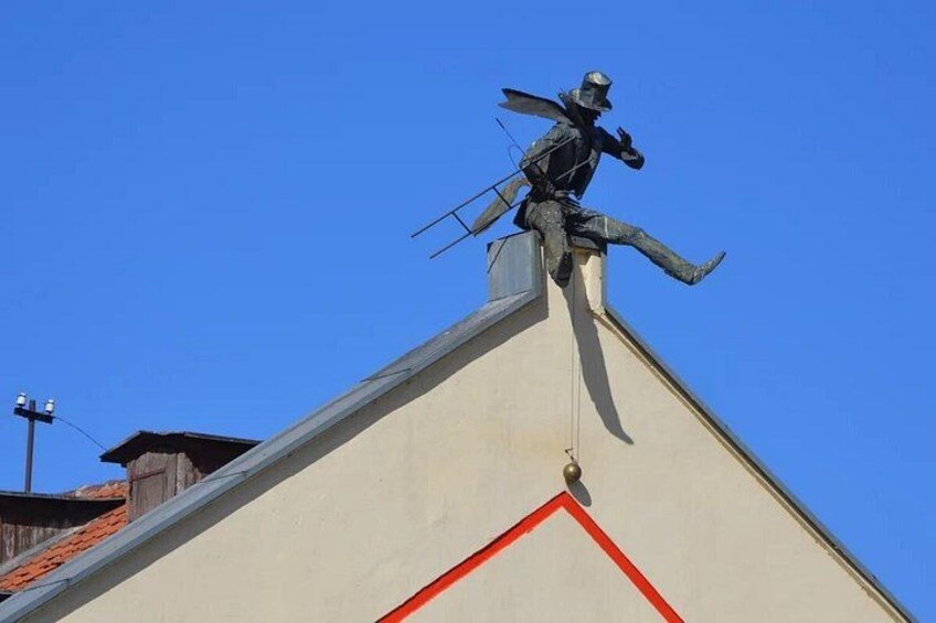 Un edificio con una estatua en la parte superior, un cielo azul claro y una línea roja en la pared. 4
