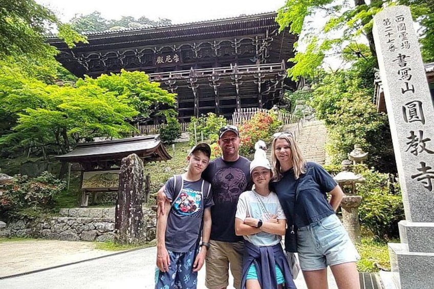 A traditional Japanese building with a curved roof, surrounded by lush greenery and stone pathways. 2