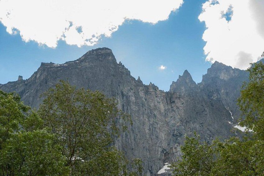 A mountain range with a prominent peak, surrounded by green trees. 2