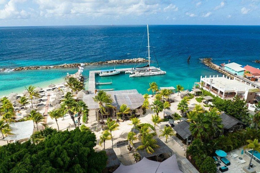 A coastal resort with a marina, palm trees, and a clear blue sea. 3