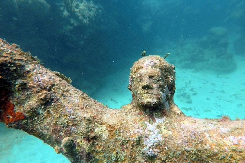 A submerged statue with a fish on its head, surrounded by underwater flora. 3
