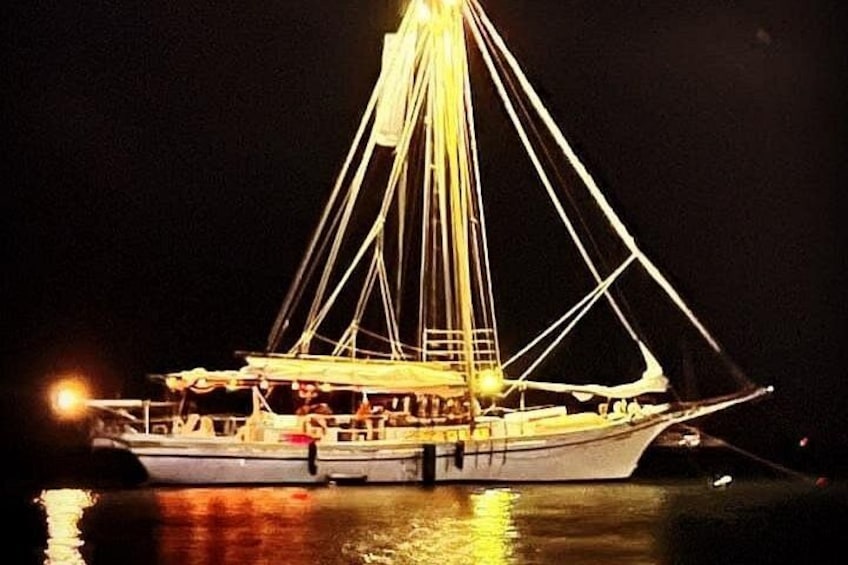 A boat with a mast and rigging, docked at night. 3