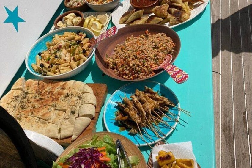 A variety of dishes including pasta, skewers, and a salad on a table. 4