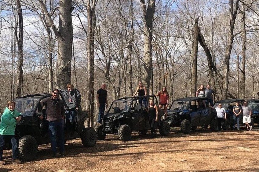 Un grupo de personas de pie junto a vehículos todo terreno en un área boscosa. 2