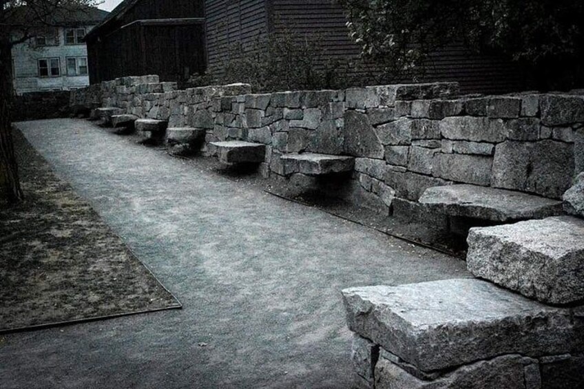 A stone bench area with steps leading up to a building. 1