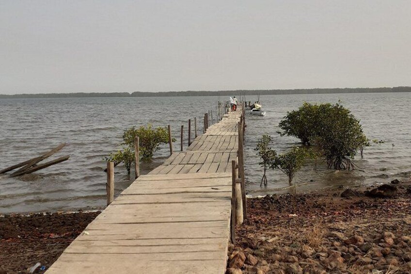 Un muelle de madera se adentra en aguas tranquilas, con un barco amarrado al final. 3