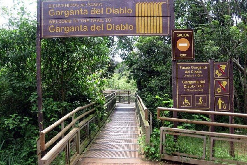 Un puente de madera que lleva a la entrada de un sendero, con señales que indican el camino a la Garganta del Diablo. 5