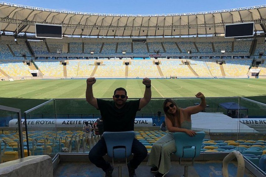 A stadium with empty stands, a person sitting on a chair, and another person standing with arms raised. 3