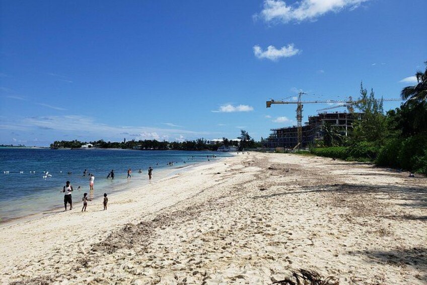 A beach with people walking, a construction crane, and buildings in the background. 4